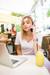 © F8  \ Suport Ukraine - Young beauty woman talks with boss via cell phone, looking screen of laptop computer, with fresh cocktail, works remotely during rest in resort