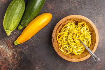 Wall Mural - Raw vegan zucchini noodles in a wooden bowl, top view, dark background