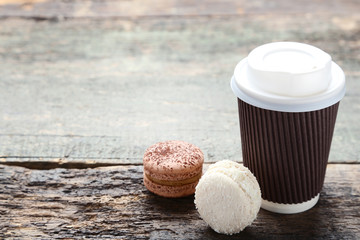 Wall Mural - Paper cup of coffee with sweet macarons on grey wooden table