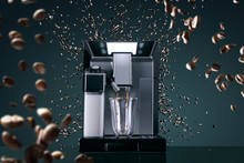 Coffee Machine With Flying Coffee Beans Across It On Dark Background. Concept Studio Shooting. High Speed Freezing Photo