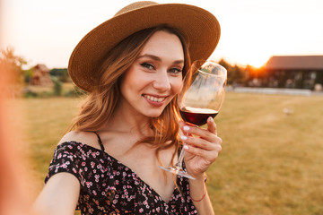 Poster - Woman outdoors holding glass drinking wine.