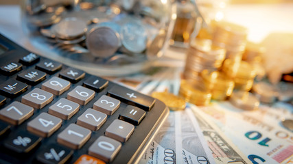 Wall Mural - Calculator with currency glass jar and gold coins stack, dollar and euro banknotes on the table. Compound interest rate calculation or financial investment business concepts