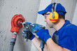 © Kadmy - electrician at work. boring hole for electric outlet by power tool drill.
