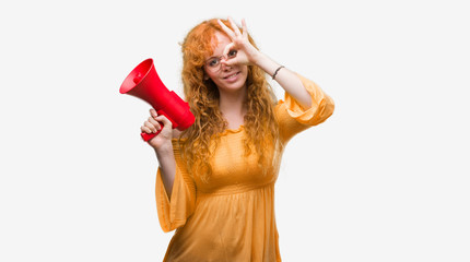 Poster - Young redhead woman holding megaphone with happy face smiling doing ok sign with hand on eye looking through fingers