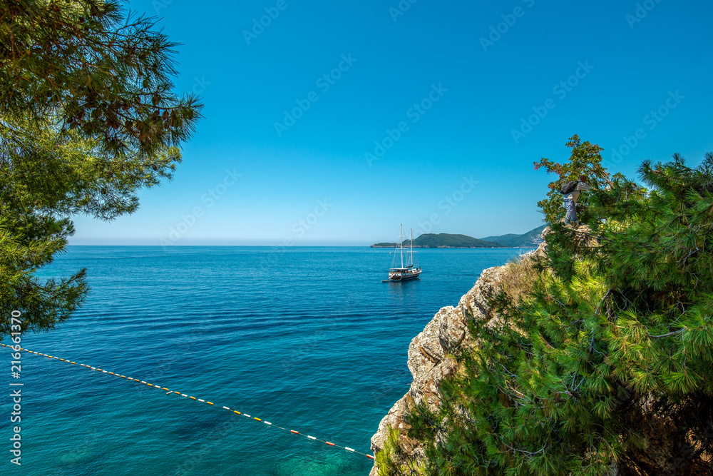 Piękna zatoka morska w lecie. Jacht na tle wyspy St Stefan Morze Adriatyckie, Czarnogóra. - obrazy, fototapety, plakaty 