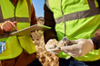 © Seventyfour - Mid-section portrait of two unrecognizable industrial workers wearing reflective jackets, one of them African, inspecting mineral ore on site outdoors and using digital tablet