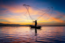 Silhouette Of Myanmar Fisherman On Wooden Boat ,Myanmar Fisherman In Action Catching Freshwater Fish In Nature River, Myanmar Traditional Fishermen At The Sunset Near Inle Lake,Myanmar