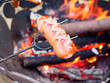 Fleisch Wurst auf einem Grillspieß über einem Lagerfeuer