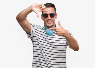 Sticker - Handsome young man wearing headphones smiling making frame with hands and fingers with happy face. Creativity and photography concept.