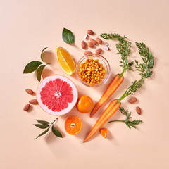 Natural organic citrus fruits, carrots, sea buckthorn berries - ingredients for making homemade detox smoothie on yellow paper background.