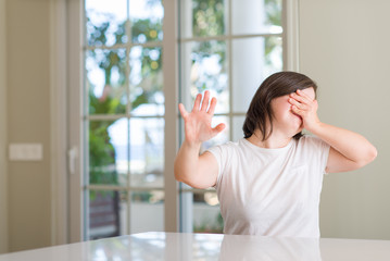 Sticker - Down syndrome woman at home covering eyes with hands and doing stop gesture with sad and fear expression. Embarrassed and negative concept.