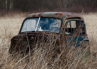 Old truck cab abandoned in field.