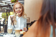 © fotofabrika - Two beautiful young girls sitting by the table in cafe