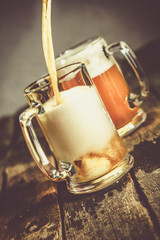 Wall Mural - Pouring beer in glasses on rustic background