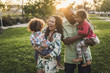 © Cavan Images - Cheerful parents carrying children on field at park during sunset