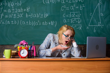 Wall Mural - Work far beyond actual school day. Teacher busy with paperwork and research. Teacher tired face keep working after classes. Still working. Teacher woman sit table classroom chalkboard background