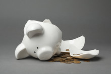 Broken Piggy Bank With Coins On Gray Background