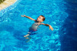 © nata_zhekova - Happy kid playing in blue water of swimming pool on a tropical resort at the sea. Summer vacations concept. Cute boy swimming in pool water
