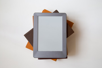 E-book reader device on desk in library. Alternative for traditional books