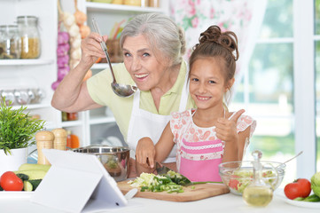 grandmother and granddaughter preparing dinner 