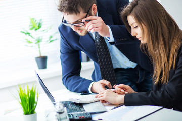 Young businessman discussing something with his colleague, and using a digital laptop together