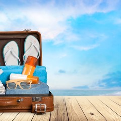 retro suitcase with travel objects on sea