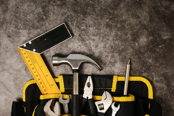 Construction worker belt with tools on concrete texture background.