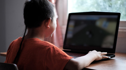 Asian boy 7 years old using laptop playing the game with Internet Information at home. Concept of technology in everyday life.