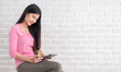 © weedezign - Asian woman in casual cloth holding credit card and using to online shopping with tablet at white brick wall.Digital technology lifestyle.Banner with copy space for display text or design.