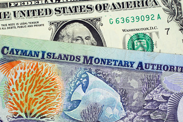 Sticker - A close up image of a colorful Cayman Islands dollar bill with an American one dollar bill