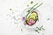 Toast avocado puree, cucumber, onion, onion flowers, radish and daikon on slices of dark bread on a light background with sesame seeds. Top view, copy space.