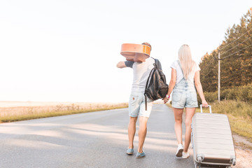 Sticker - A loving couple walks along the road with a guitar and suitcases and catches a car hitchhiking.