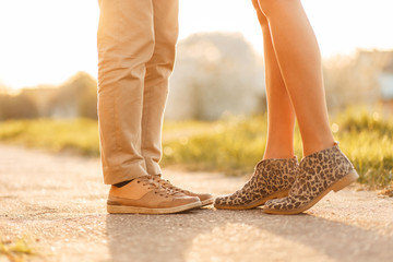 Young love couple kissing at sunset. Legs with shoes close-up