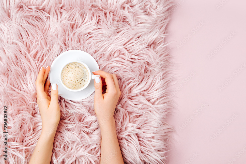 Female hands holding a cup of coffee on the fluffy fur plaid.  Flat lay, top view - obrazy, fototapety, plakaty 