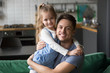 © fizkes - Portrait of happy dad hugging kid cute daughter looking at camera at home, smiling young daddy embracing cute girl expressing love and care, good single father posing with his child indoors concept