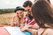 group of happy young friends planning car trip with map on engine hood