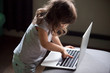 © fizkes - Curious smart little girl typing on laptop alone, clever cute child using computer online without permission, forbidden internet content parental protection, pc control and security for kid concept