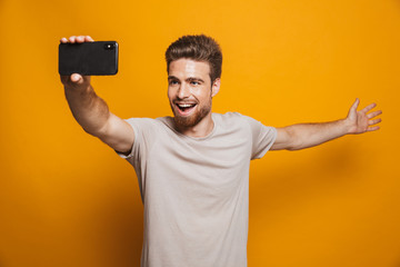 Wall Mural - Man standing isolated make a selfie by smartphone showing copyspace.