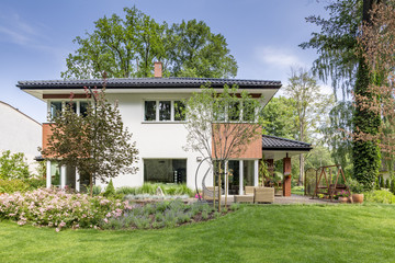 Wall Mural - Flowers and trees in the garden of white house with windows during summer