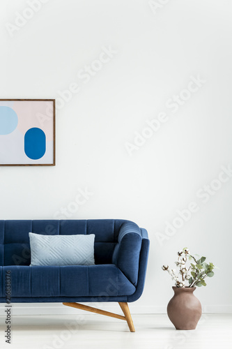 Plant Next To Navy Blue Couch With Cushion In White Living Room