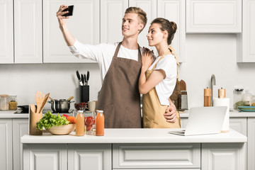 Wall Mural - young couple taking selfie with smartphone in kitchen