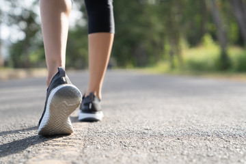 Wall Mural - Runner feet running on road closeup on shoe. Woman fitness sunrise jog workout welness concept. Young fitness woman runner athlete running at road