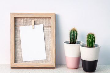 Desk in terrazzo pattern with two cactuses in pots with a wooden frame against a white wall