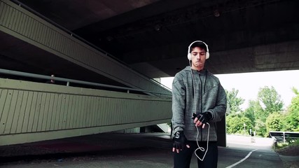 Canvas Print - Young sporty man with headphones in the city, listening to music and dancing.