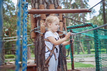 portrait of a little blond girl in rope park.