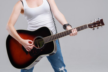 Wall Mural - Closeup of young woman hands playing acoustic guitar at the studio