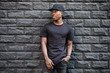 © antgor - Handsome african american man in blank black t-shirt standing against brick wall