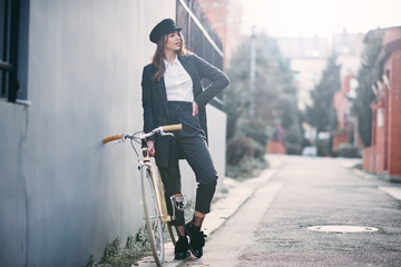 Wall Mural - Woman standing on the street next to her fixie bicycle.