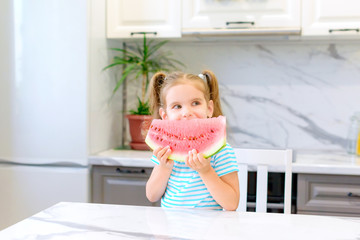 Wall Mural - child eats watermelon. happy baby girl eating watermelon in summer in the kitchen. selective focus.