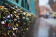 thousands of colored padlocks on the emerald iron fence of the bridge on the blurred background of the crowded street of Wroclaw in Poland.
